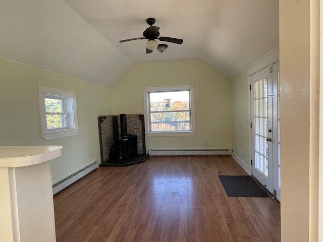 unfurnished living room with a wood stove, dark hardwood / wood-style floors, a baseboard radiator, and vaulted ceiling