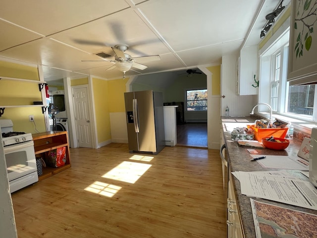 kitchen featuring ceiling fan, stainless steel refrigerator with ice dispenser, light wood-type flooring, and gas range gas stove