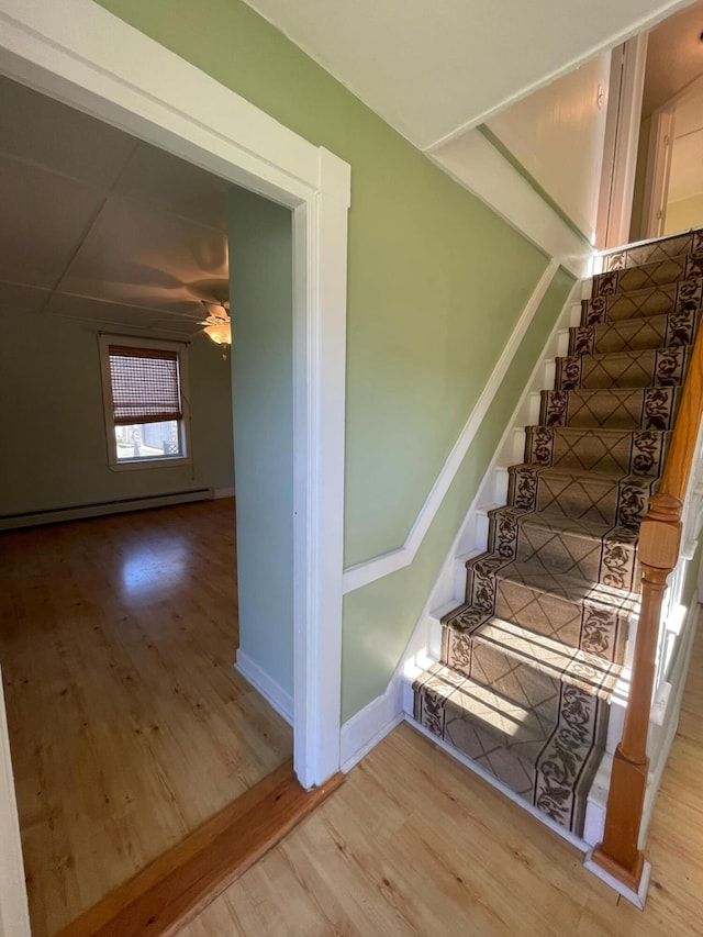 stairway featuring hardwood / wood-style floors, a baseboard radiator, and ceiling fan