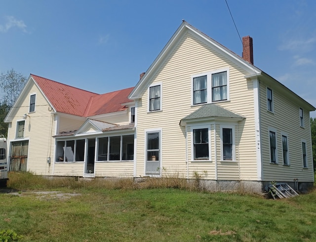 rear view of property featuring a sunroom and a lawn