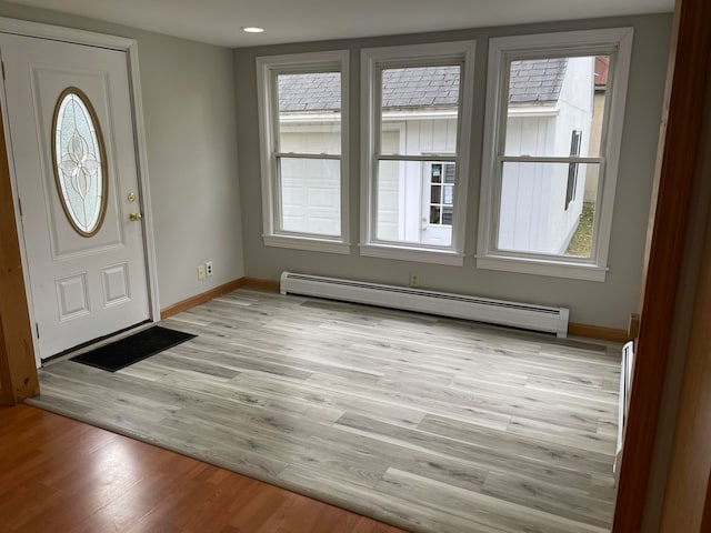 foyer entrance with baseboard heating, plenty of natural light, and light hardwood / wood-style flooring