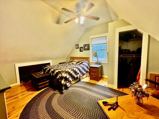 bedroom with ceiling fan, a spacious closet, lofted ceiling, a closet, and light wood-type flooring