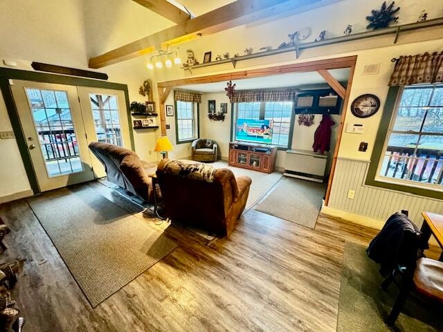 living room featuring beam ceiling, wood-type flooring, and a wealth of natural light