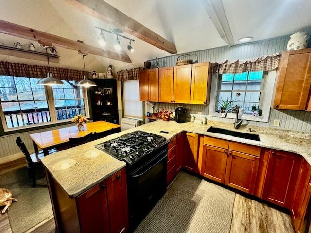 kitchen with light stone countertops, black range oven, sink, beamed ceiling, and hanging light fixtures