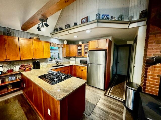 kitchen featuring sink, light stone countertops, light wood-type flooring, appliances with stainless steel finishes, and beam ceiling