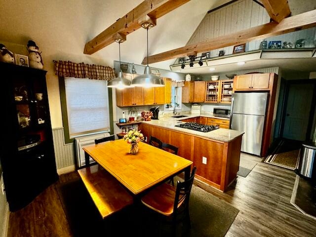 kitchen featuring beam ceiling, sink, hanging light fixtures, stainless steel appliances, and hardwood / wood-style floors