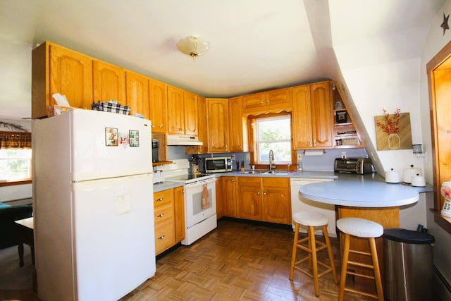 kitchen with a kitchen breakfast bar, kitchen peninsula, parquet flooring, sink, and white appliances