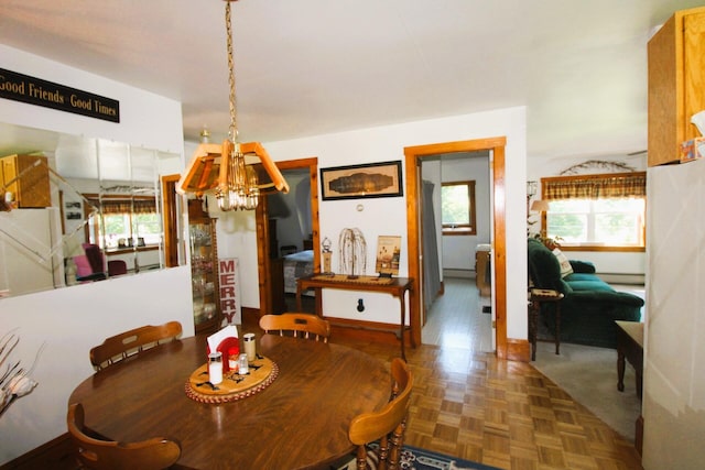 dining area featuring dark parquet floors and an inviting chandelier