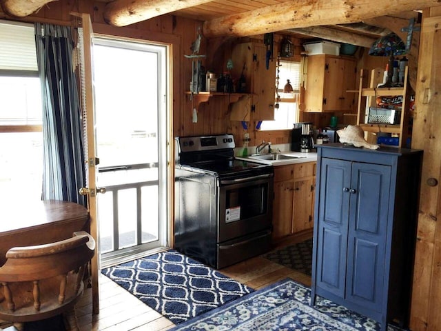 kitchen with hardwood / wood-style flooring, beam ceiling, black range with electric cooktop, sink, and wood walls