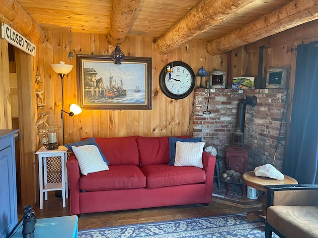 living room featuring a wood stove, wood walls, beam ceiling, and wooden ceiling