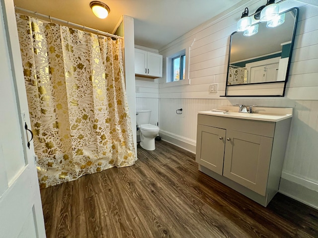 bathroom featuring toilet, a shower with shower curtain, wood finished floors, and vanity