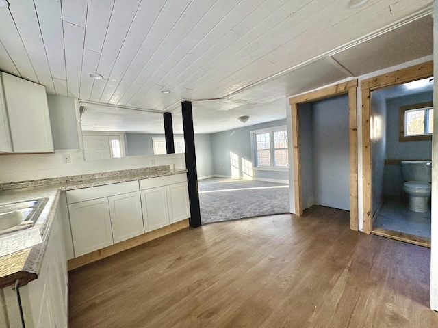 kitchen with wooden ceiling, hardwood / wood-style floors, white cabinets, and sink