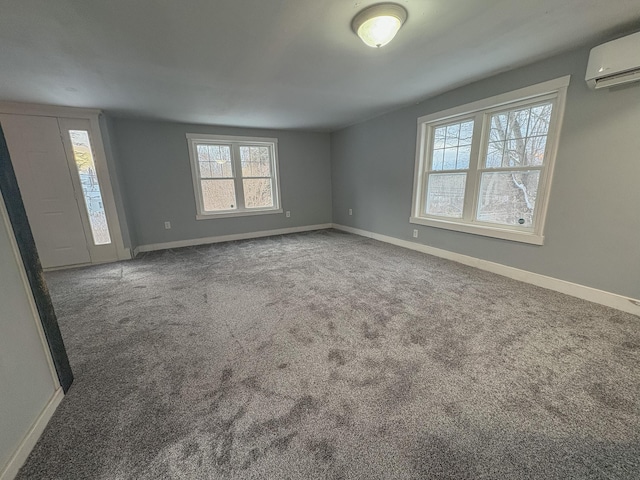 interior space with carpet floors, baseboards, and an AC wall unit