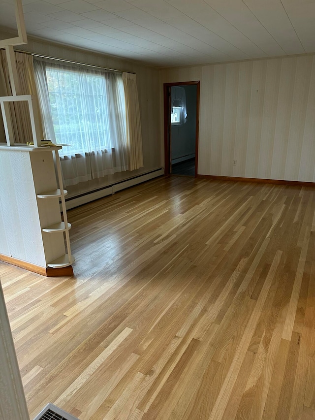 unfurnished room with wood-type flooring and a baseboard radiator