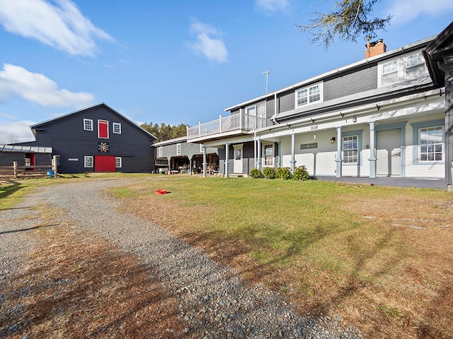 rear view of house featuring a yard, a balcony, and covered porch