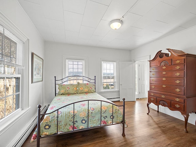 bedroom with wood-type flooring and a baseboard heating unit