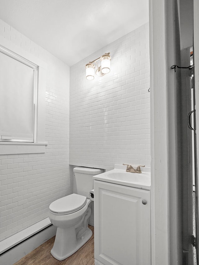 bathroom featuring vanity, wood-type flooring, tile walls, and a baseboard heating unit