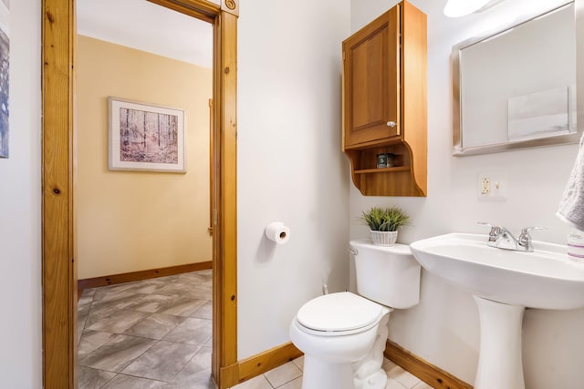 bathroom with toilet, sink, and tile patterned flooring