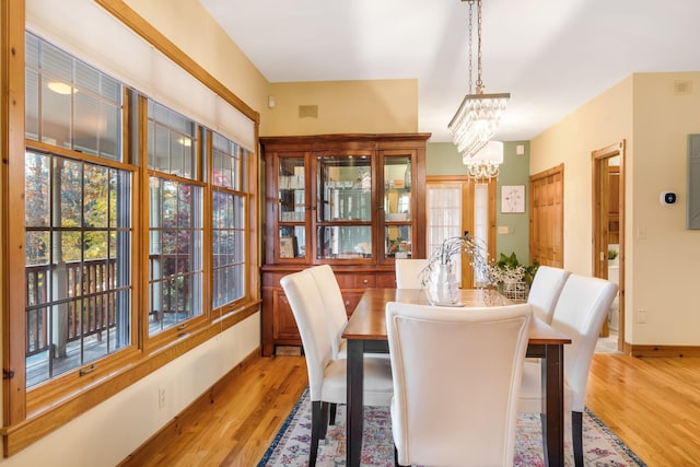 dining area with light hardwood / wood-style floors and an inviting chandelier