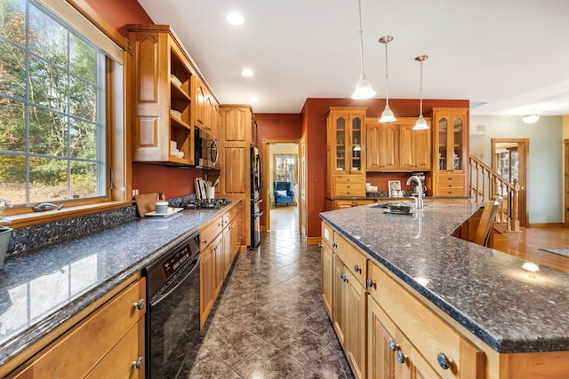 kitchen featuring pendant lighting, a large island with sink, black appliances, and plenty of natural light