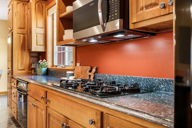 kitchen featuring gas cooktop, light tile patterned floors, and dark stone counters