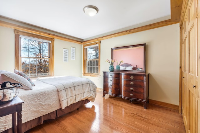 bedroom featuring light hardwood / wood-style flooring, multiple windows, and a closet