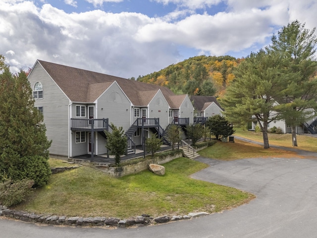 view of front of house with a deck with mountain view and a front lawn