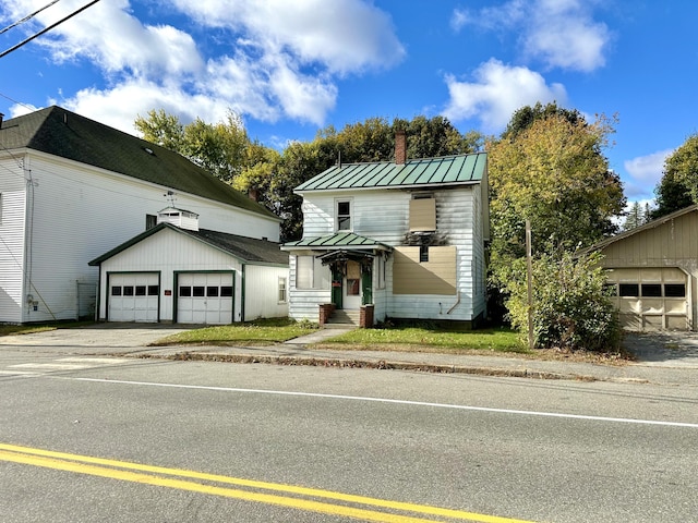 35 Roxbury Rd, Mexico, ME 04257 - view of front of property with a chimney, a standing seam roof, an outbuilding, metal roof, and a garage
