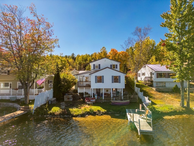 rear view of property with a water view, a lawn, and a balcony