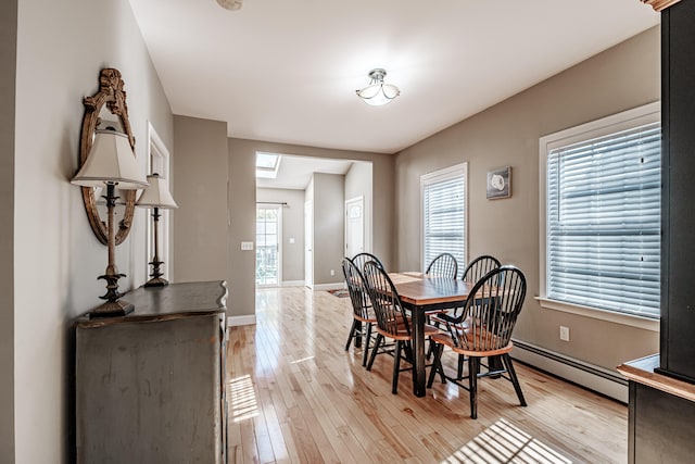 dining room featuring plenty of natural light, light wood-type flooring, and a baseboard heating unit