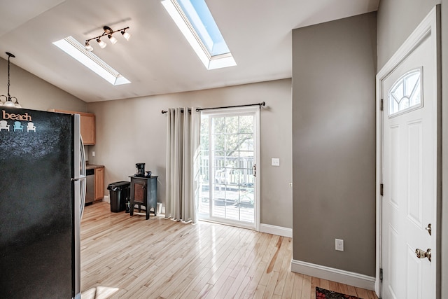 kitchen with stainless steel fridge, light hardwood / wood-style flooring, and vaulted ceiling with skylight