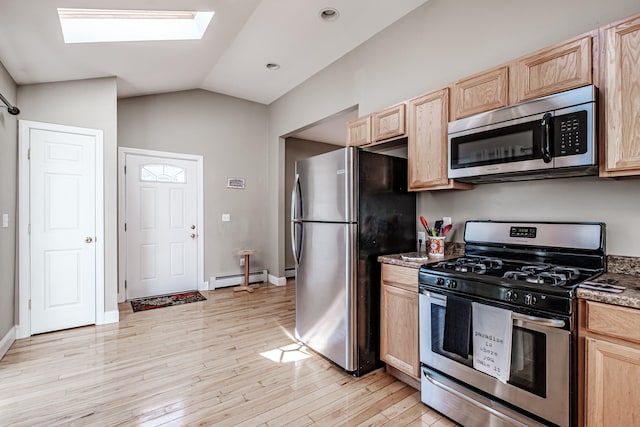 kitchen featuring light brown cabinetry, vaulted ceiling with skylight, a baseboard heating unit, and appliances with stainless steel finishes