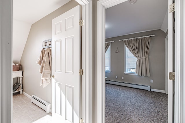 interior space featuring vaulted ceiling, light carpet, and a baseboard heating unit