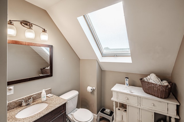 bathroom featuring lofted ceiling with skylight, vanity, and toilet