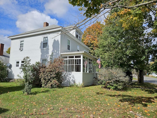 view of side of home with a sunroom and a lawn