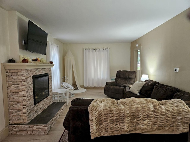 living room with light wood-type flooring and a stone fireplace