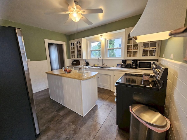 kitchen featuring a kitchen island, sink, tile walls, appliances with stainless steel finishes, and white cabinetry