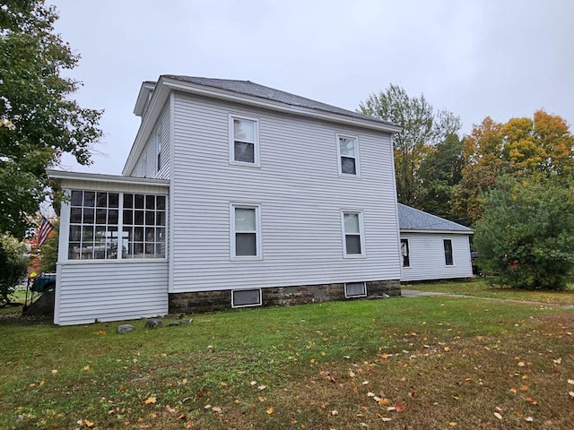 back of house featuring a sunroom and a lawn