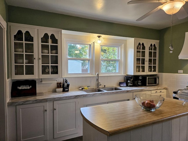 kitchen featuring decorative backsplash, white cabinets, sink, and a center island