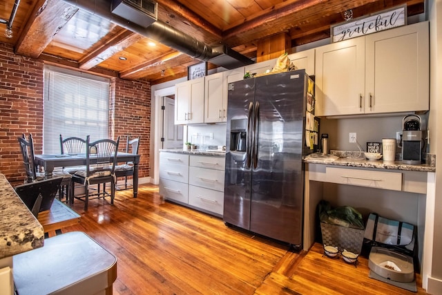 kitchen featuring brick wall, wooden ceiling, light wood-type flooring, and stainless steel refrigerator with ice dispenser