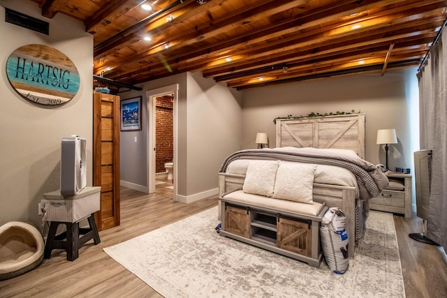 bedroom with light hardwood / wood-style floors, wood ceiling, beam ceiling, and ensuite bathroom