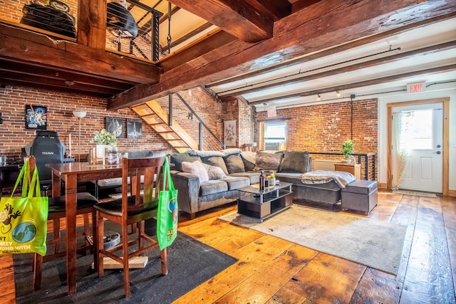 living room featuring light hardwood / wood-style flooring, beamed ceiling, and brick wall