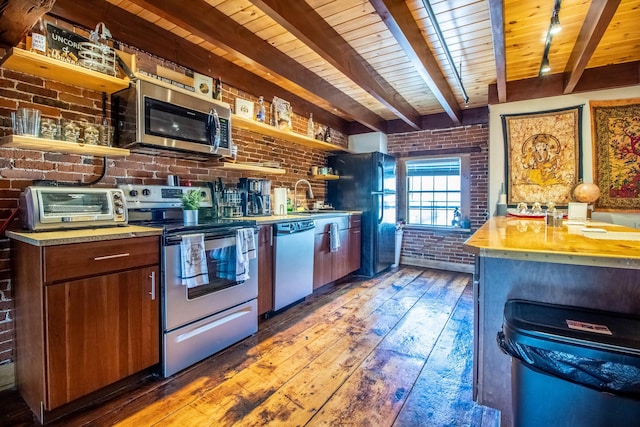 kitchen with brick wall, appliances with stainless steel finishes, and dark hardwood / wood-style floors