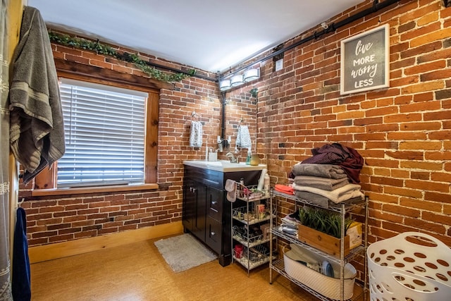 bathroom featuring vanity, brick wall, and hardwood / wood-style floors