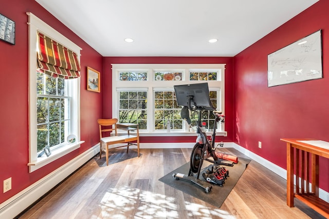 exercise room featuring baseboard heating and wood-type flooring