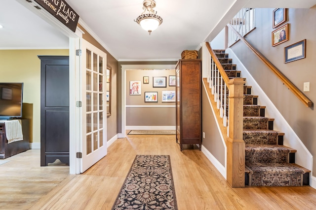 foyer with crown molding and light hardwood / wood-style flooring