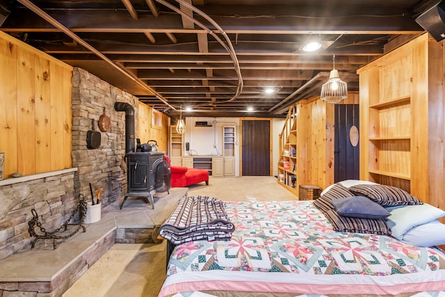 bedroom with concrete floors, wooden walls, and a wood stove