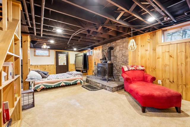 basement with wood walls, carpet flooring, a wood stove, and plenty of natural light