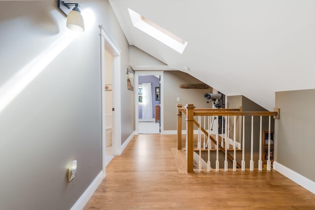 hall featuring lofted ceiling with skylight and light hardwood / wood-style flooring