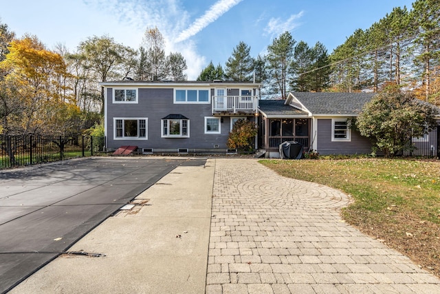 view of front of house featuring a front yard, a sunroom, and a balcony